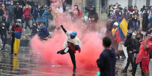 An anti-government protester returns a tear gas canister at the police during clashes in Bogota, Colombia, May 5, 2021 (AP photo by Fernando Vergara).