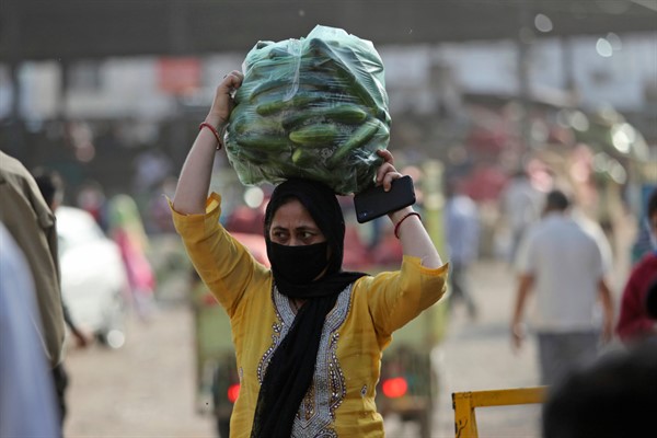 A woman carries vegetables outside a wholesale market in Jammu, India, May 2, 2020 (AP photo by Channi Anand).