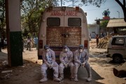 Exhausted workers who carried the dead for cremation sit on the rear step of an ambulance in New Delhi, India, April 24, 2021 (AP photo by Altaf Qadri).