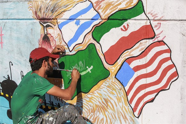 A man paints Israeli, Iranian, U.S. and Saudi Arabia national flags on a wall during an anti-government protest in Baghdad, Iraq, Nov. 17, 2019 (Photo by Ameer Al Mohammedaw for dpa via AP Images).