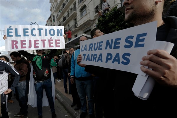 Algerian demonstrators protest the 2019 presidential election with banners in French that read “reject the election” and “the street will not be quiet,” in Algiers, Dec. 12, 2019 (AP photo by Toufik Doudou).
