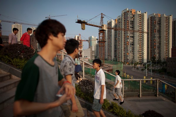 Students and migrant workers walk near a construction site at Chongqing University of Posts and Telecommunications, in Chongqing, China (AP photo by Alexander F. Yuan).
