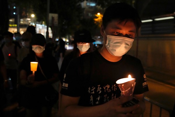 People walk with candles to mark the anniversary of the Tiananmen Square massacre, outside Victoria Park in Hong Kong, June 4, 2021 (AP photo by Kin Cheung).