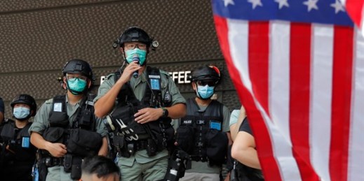 Riot police stand guard in front of an American flag near the U.S. Consulate in Hong Kong, July 4, 2020 (AP photo by Kin Cheung).