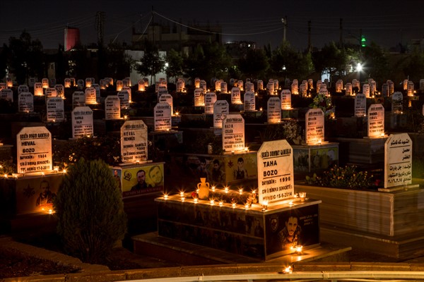 Candles on the graves of people killed during the Syrian war, in the town of Qamishli, Syria, Oct. 31, 2019 (AP photo by Baderkhan Ahmad).