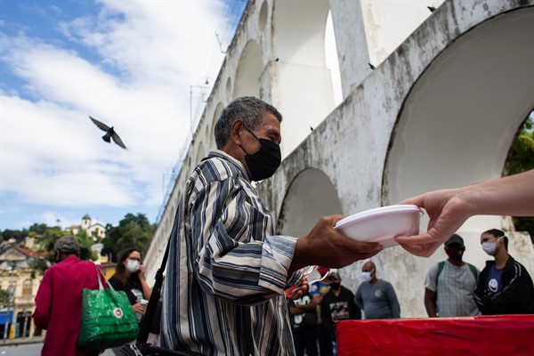 People line up for a free, cooked meal in Rio de Janeiro, Brazil, April 29, 2021 (AP photo by Bruna Prado).