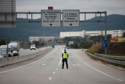 A police officer stands on a closed-off road near Igualada, Spain, March 13, 2020 (AP photo by Joan Mateu).