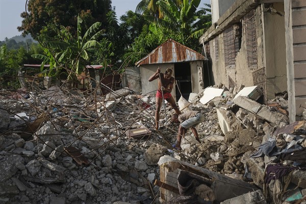 A man searches for his passport among the wreckage of his grandmother’s collapsed house, in Maniche, Haiti, Aug. 24, 2021 (AP photo by Matias Delacroix).