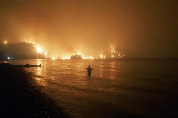 A man watches as wildfires approach Kochyli beach near Limni village on the island of Evia, about 100 miles north of Athens, Greece, Aug. 6, 2021 (AP photo by Thodoris Nikolaou).