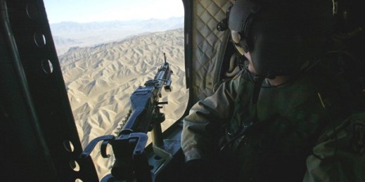 A U.S. Army doorgunner aboard a Chinook helicopter looks down onto the Afghan landscape enroute to the inauguration ceremony for a Coalition-led Provincial Reconstruction Team outpost in Asadabad, Feb. 19, 2004 (AP photo by Bob Strong).