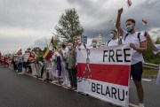 Supporters of Belarus’ opposition from Lithuania wave historical Belarusian flags near Medininkai, east of Vilnius, Lithuania, Aug. 23, 2020 (AP photo by Mindaugas Kulbis).