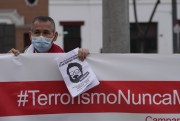 A man helps hold up a banner with a hashtag that reads in Spanish, “terrorism never again,” as he joins others outside the anti-terrorism directorate to celebrate the death of Abimael Guzman, in Lima, Peru, Sept. 11, 2021 (AP photo by Martin Mejia).