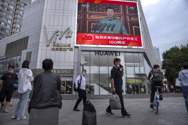 People walk past a large video screen outside a shopping mall showing Chinese President Xi Jinping speaking during an event to commemorate the 100th anniversary of China’s Communist Party in Beijing, July 1, 2021 (AP photo by Mark Schiefelbein).