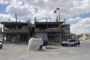 Russian and Syrian flags fly over a damaged building in the southern city of Deraa, Syria, Sept. 12, 2021 (AP photo).