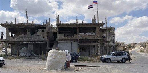 Russian and Syrian flags fly over a damaged building in the southern city of Deraa, Syria, Sept. 12, 2021 (AP photo).