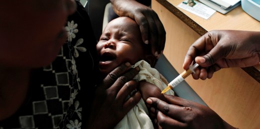 A mother holds her baby receiving a malaria vaccine.