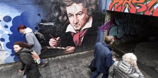 People passing a graffiti mural showing composer Ludwig van Beethoven on a street in Bonn, Germany, Feb. 19, 2020 (AP photo by Martin Meissner).
