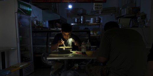 A man uses his smartphone flashlight to eat his breakfast at a restaurant during a blackout in Shenyang, Liaoning province, China, Sept. 29, 2021 (AP photo by Olivia Zhang).