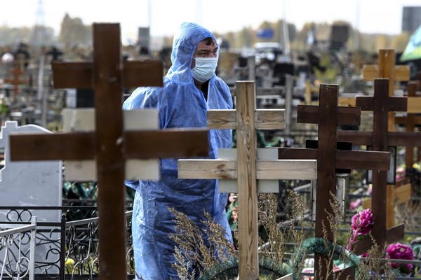 A grave digger wears a protective suit during a burial for a person who died of COVID-19, at a cemetery in Omsk, Russia, Oct. 7, 2021 (AP photo).