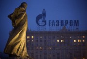 A monument to Ukrainian poet and writer Taras Shevchenko is silhouetted against an apartment building with a sign for Russia’s natural gas giant Gazprom, in Moscow, Russia, March 4, 2014 (AP photo by Alexander Zemlianichenko).