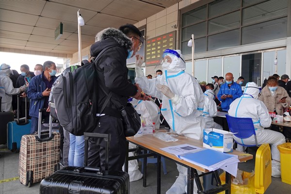 Medical workers take swab samples of arriving travelers at the exit of a railway station in Yantai, Shandong province, China, Nov. 2, 2021 (FeatureChina photo via AP Images).