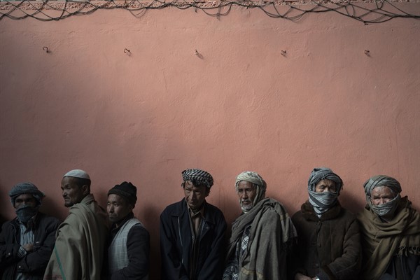 Afghan men wait in line to receive cash at a money distribution organized by the World Food Program in Kabul, Nov. 3, 2021 (AP photo by Bram Janssen).