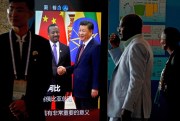African delegates walk by a screen panel showing an image of Chinese President Xi Jinping with Ethiopian Prime Minister Abiy Ahmed ahead of the 2018 Forum on China-Africa Cooperation, Beijing, Sept. 3, 2018 (AP photo by Andy Wong).