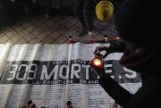 Advocates for migrants’ rights light candles in front of a banner that reads, “309 dead on the France-U.K. border since 1999,” during a gathering outside the port of Calais, northern France, Nov. 25, 2021 (AP photo by Rafael Yaghobzadeh).