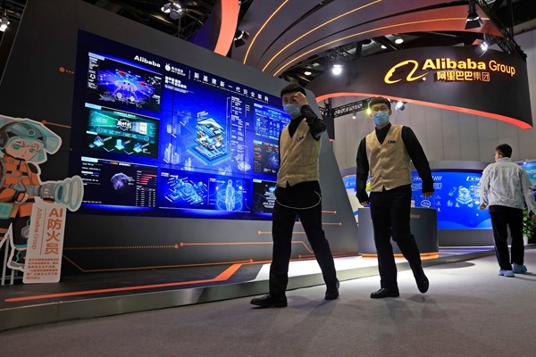 Employees walk past the logo for Alibaba Group during an Internet Technology Expo in Beijing, April 30, 2021 (AP photo by Ng Han Guan).