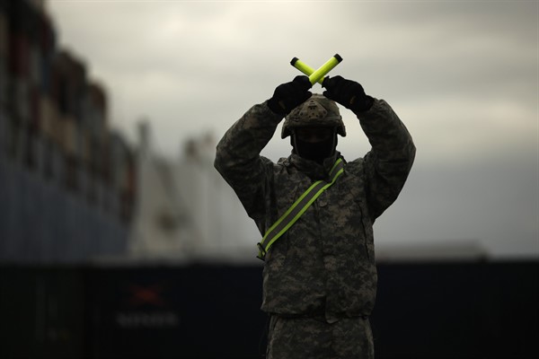 A U.S. soldier directs armored vehicles and tanks of the 1st Armored Brigade Combat Team and 1st Calvary Division as they are unloaded at the port of Antwerp, Belgium, Nov. 16, 2020 (AP photo by Francisco Seco).