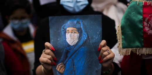 A woman holds a photograph during a protest to raise awareness about the situation in Afghanistan, outside EU headquarters in Brussels, Aug. 18, 2021 (AP photo by Francisco Seco).