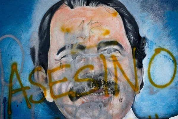 The Spanish word for “murderer” covers a mural of Nicaraguan President Daniel Ortega, as part of anti-government protests demanding his resignation in Managua, Nicaragua, May 26, 2018 (AP photo by Esteban Felix).