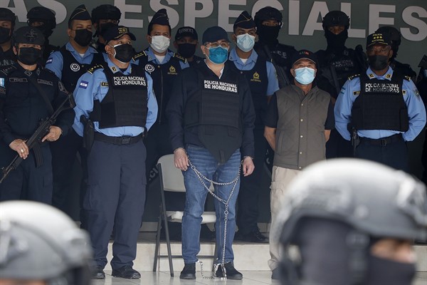 Former Honduran President Juan Orlando Hernandez, center in chains, is shown to the press at the Police Headquarters in Tegucigalpa, Honduras, Feb. 15, 2022 (AP photo by Elmer Martinez).