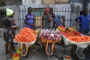 A woman buys tomatoes and onions from street-sellers in Lagos, Nigeria, April 13, 2020 (AP photo by Sunday Alamba).
