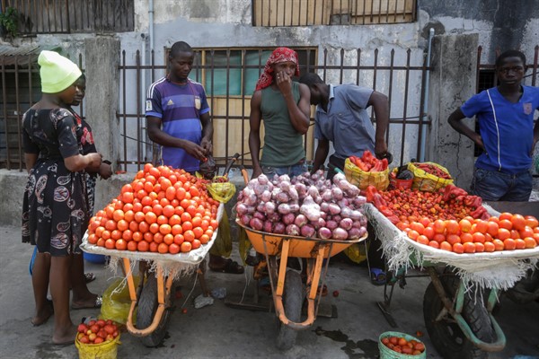 A woman buys tomatoes and onions from street-sellers in Lagos, Nigeria, April 13, 2020 (AP photo by Sunday Alamba).