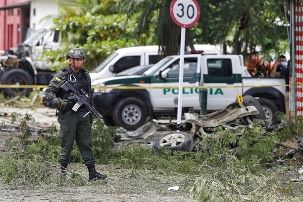 A police officer walks by the wreckage of a car bomb that exploded near a police station in Padilla, Cauca, Colombia, Feb.6 2022 (AP photo by Andres Gonzalez).