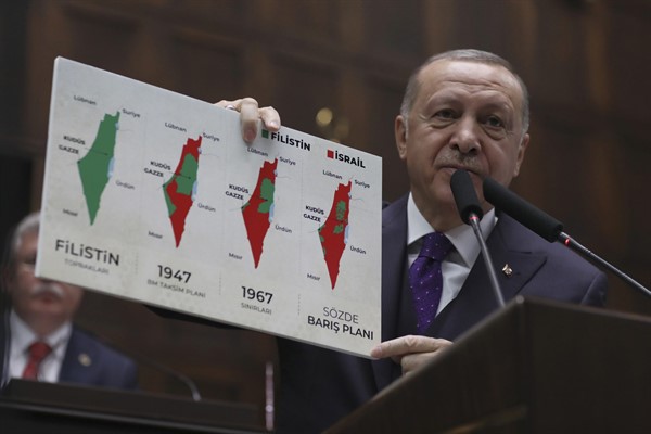 Turkish President Recep Tayyip Erdogan holds up a placard displaying maps of historical Palestine during a speech at the parliament, Ankara, Turkey, Feb. 5, 2020 (AP photo by Burhan Ozbilici).