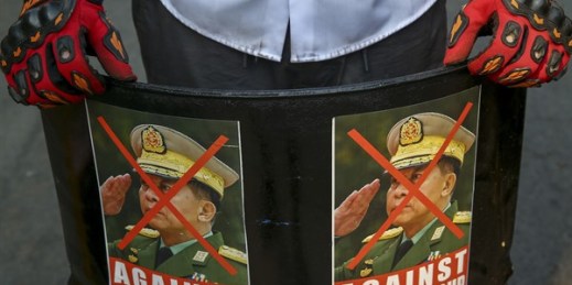 An anti-coup protester displays defaced images of commander-in-chief Gen. Min Aung Hlaing in Mandalay, Myanmar, March 3, 2021 (AP Photo).