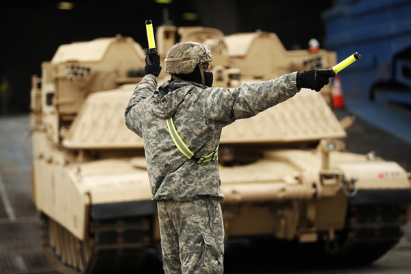 A U.S. soldier directs armored vehicles and tanks as they are unloaded at the port of Antwerp, Belgium, Nov. 16, 2020 (AP photo by Francisco Seco).