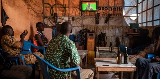 People gather in a bar to watch the presidential inauguration of Junta leader Lt. Col. Paul Henri Sandaogo Damiba during his swearing-in ceremony broadcast on national television, Ouagadougou, Burkina Faso, Feb. 16, 2022 (AP photo by Sophie Garcia).