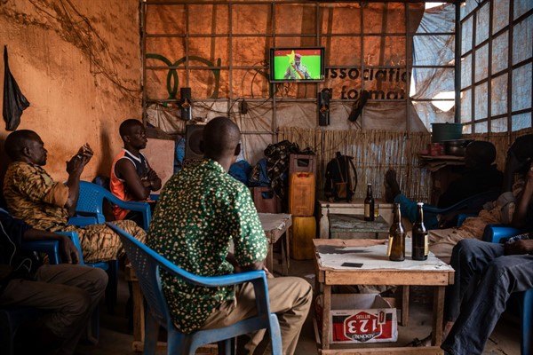 People gather in a bar to watch the presidential inauguration of Junta leader Lt. Col. Paul Henri Sandaogo Damiba during his swearing-in ceremony broadcast on national television, Ouagadougou, Burkina Faso, Feb. 16, 2022 (AP photo by Sophie Garcia).