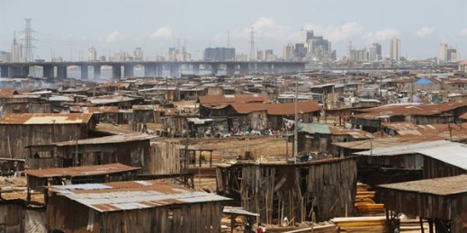 People work in a sawmill, with downtown Lagos in the distance, Lagos, Nigeria, May 12, 2020 (AP photo by Sunday Alamba).