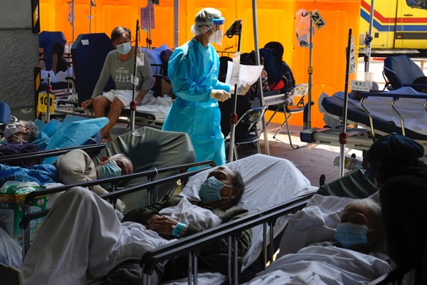 Patients in hospital beds wait in a temporary holding area outside Caritas Medical Center in Hong Kong, March 2, 2022 (AP photo by Kin Cheung).