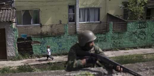 A little girl runs past soldier with his weapon drawn, during a surprise operation in the City of God slum of Rio de Janeiro, Brazil, Feb. 7, 2018 (AP photo by Leo Correa).