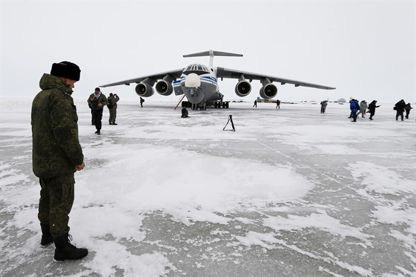 A Russian officer stands near a landed Il-76 military cargo plane on Alexandra Land, an island near Nagurskoye, Russia, May 17, 2021 (AP photo by Alexander Zemlianichenko).