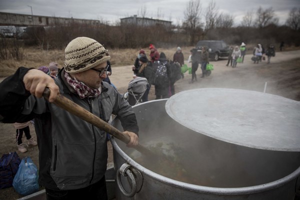 Czech volunteer Lukas Saranga cooks soup in a giant pot for refugees fleeing Ukraine at the train station at the border crossing of Medyka, Poland, March 8, 2022 (AP photo by Visar Kryeziu).
