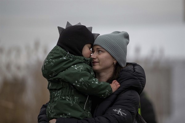 A woman hugs a child as refugees, mostly women with children, arrive from Ukraine at the border crossing in Medyka, Poland, March 6, 2022 (AP photo by Visar Kryeziu).