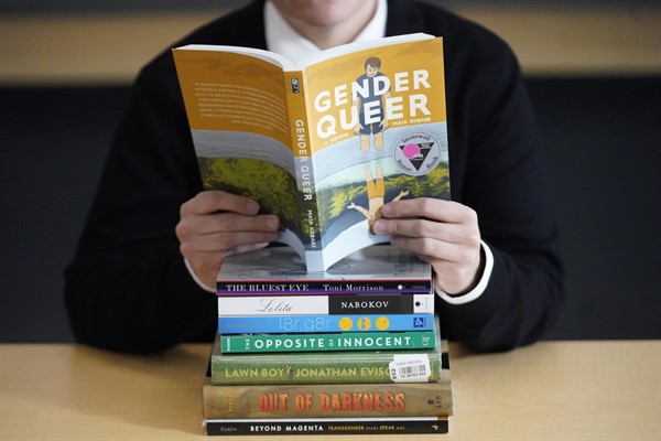 Amanda Darrow, director of youth, family and education programs at the Utah Pride Center, poses with books that have been the subject of complaints from parents in recent weeks on Dec. 16, 2021, in Salt Lake City (AP photo by Rick Bowmer).