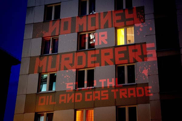 The words “No Money for Murderers, Stop the Oil and Gas Trade” are projected by activists onto the Russian consulate in Frankfurt, Germany, April 4, 2022 (AP photo by Michael Probst).