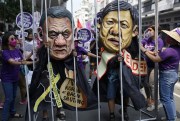 Protesters wearing masks portraying Philippine President Rodrigo Duterte and Ferdinand Marcos Jr. stand behind a mock jail during a rally near the Malacanang presidential palace in Manila, Philippines, March 8, 2022 (AP photo by Aaron Favila).